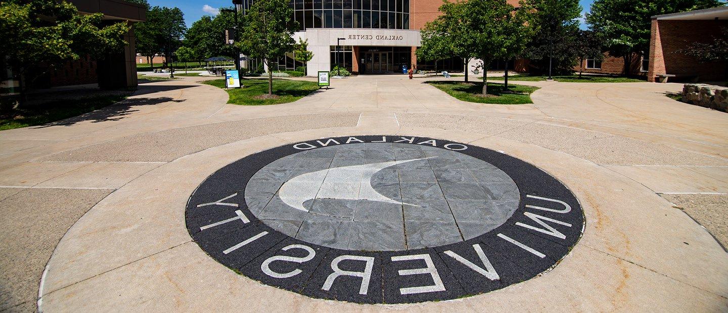Oakland University sail symbol in the concrete outside the Oakland Center building.